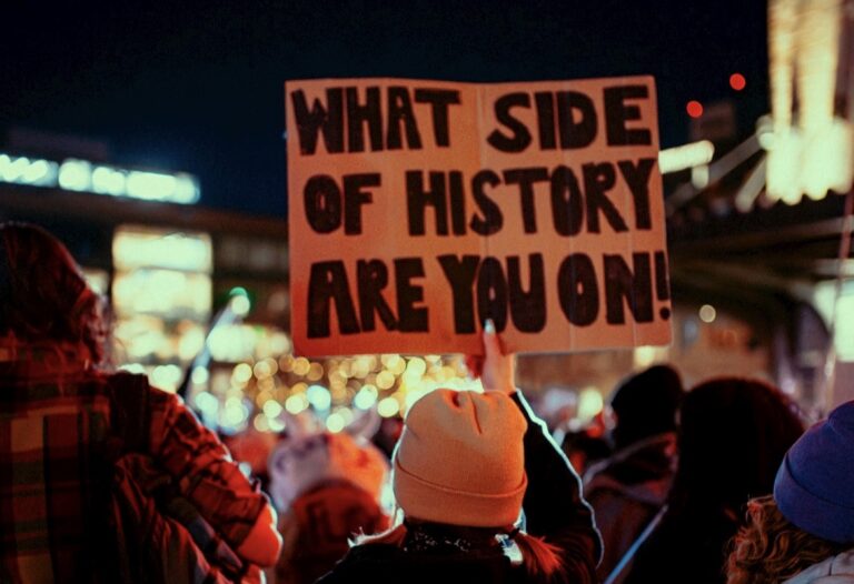 A protester hold up a sign asking, what side of history are you on?